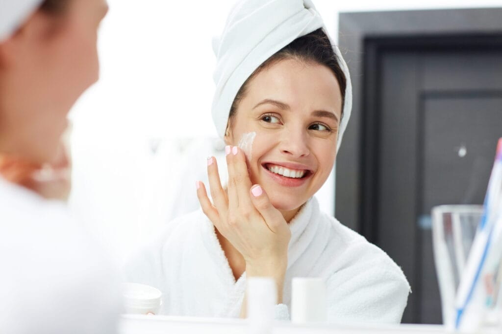 Woman applying moisturizer as part of skincare for dry skin routine