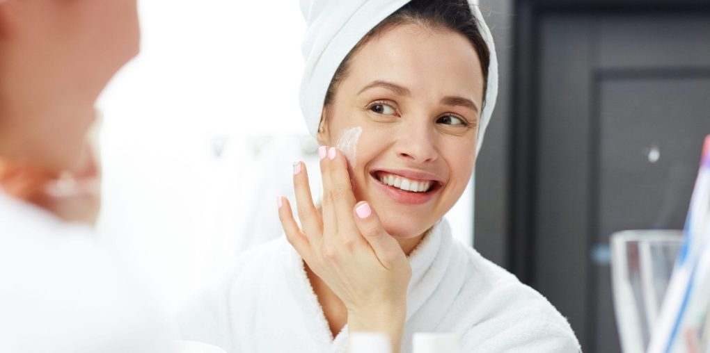 Woman applying moisturizer as part of skincare for dry skin routine