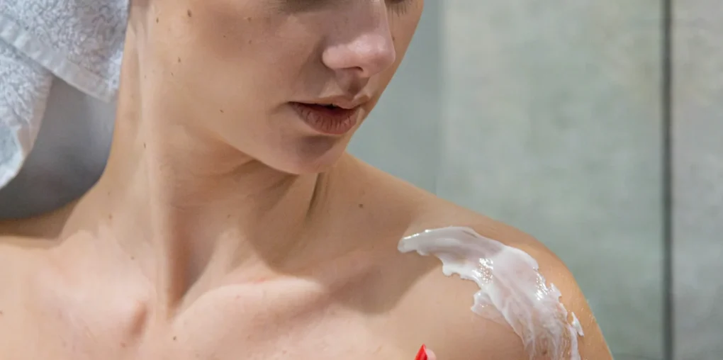 Woman applying sunscreen on shoulder, showing why sunscreen is essential for skin protection